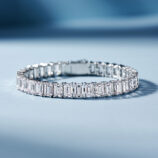Sleek tennis-style sterling silver bracelet with Emerald-cut clear stones, polished finish.