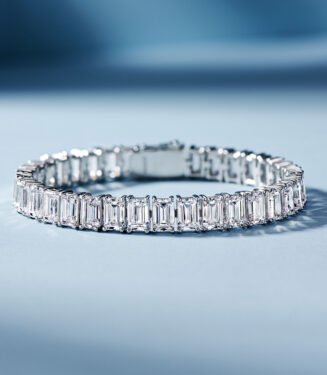 Sleek tennis-style sterling silver bracelet with Emerald-cut clear stones, polished finish.