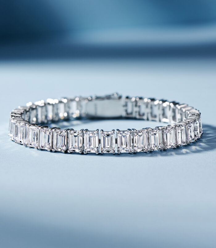 Sleek tennis-style sterling silver bracelet with Emerald-cut clear stones, polished finish.