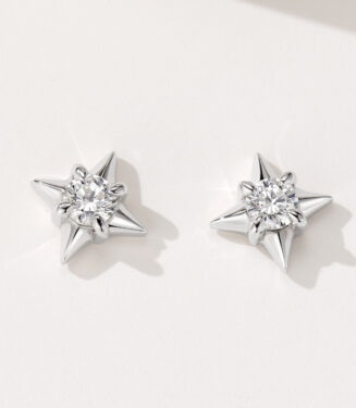 A pair of star-shaped stud earrings in polished sterling silver, featuring a central clear gemstone surrounded by six pointed silver rays, creating a celestial and sparkling design.