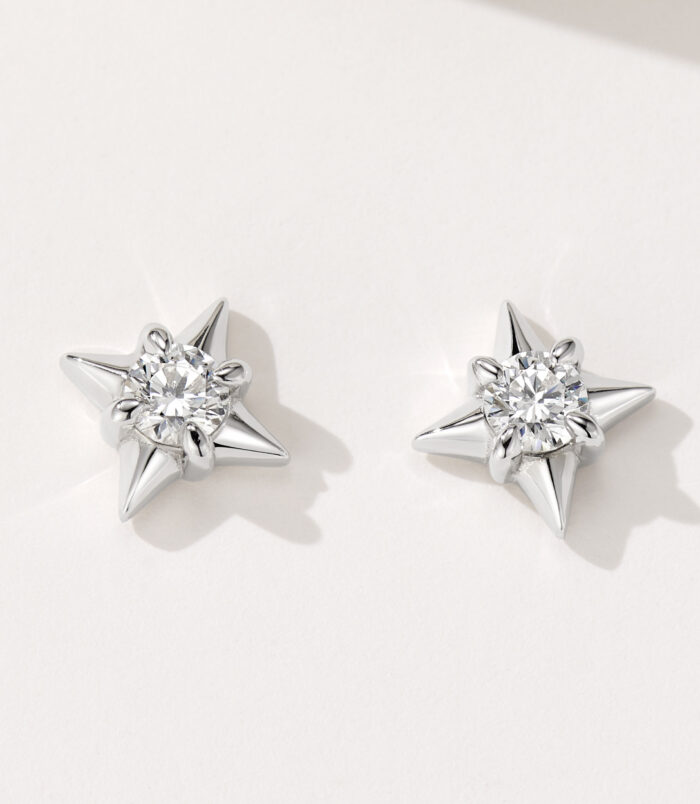 Celestial Star-Shaped Sterling Silver Stud Earrings A pair of star-shaped stud earrings in polished sterling silver, featuring a central clear gemstone surrounded by six pointed silver rays, creating a celestial and sparkling design.