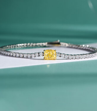 Tennis-style sterling silver bracelet with a central cushion-cut yellow stone and surrounding clear stones.