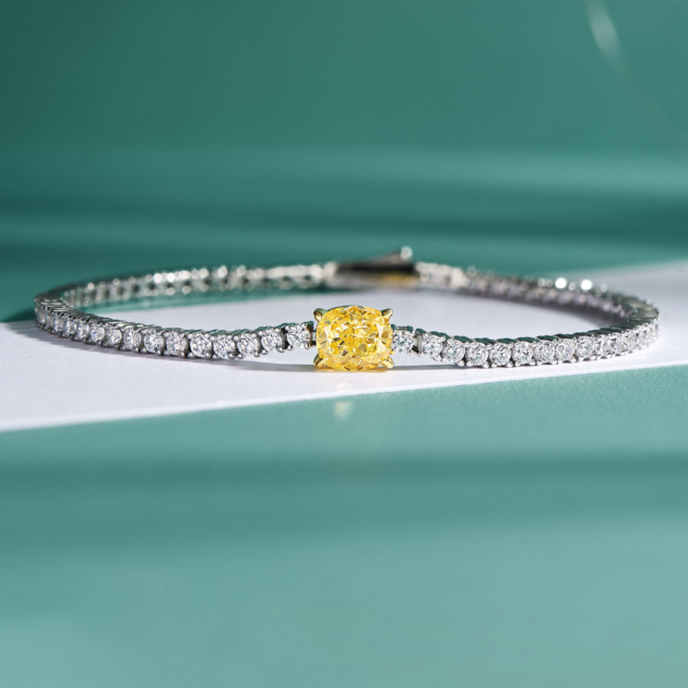 Tennis-style sterling silver bracelet with a central cushion-cut yellow stone and surrounding clear stones.