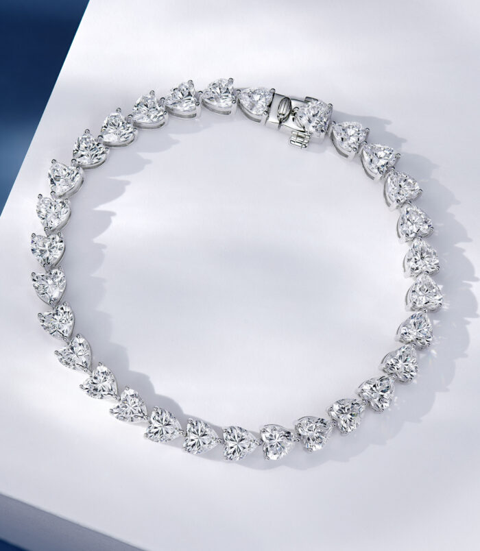 Heart-shaped cluster design sterling silver bracelet with clear stones, polished finish.