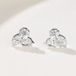 A pair of floral-shaped sterling silver stud earrings with multiple clear gemstones, displayed against a soft white background.
