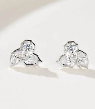 A pair of floral-shaped sterling silver stud earrings with multiple clear gemstones, displayed against a soft white background.