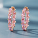 A pair of rose gold-toned hoop earrings adorned with oval-cut pink gemstones and small clear diamonds, set in polished sterling silver.