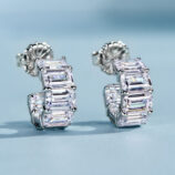 Chic sterling silver huggie hoop earrings, featuring a curved band encrusted with baguette-cut white cubic zirconia stones in a channel setting, creating a sleek and modern look perfect for adding a touch of glamour to any outfit.