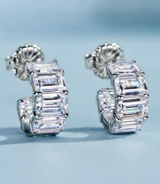 Chic sterling silver huggie hoop earrings, featuring a curved band encrusted with baguette-cut white cubic zirconia stones in a channel setting, creating a sleek and modern look perfect for adding a touch of glamour to any outfit.