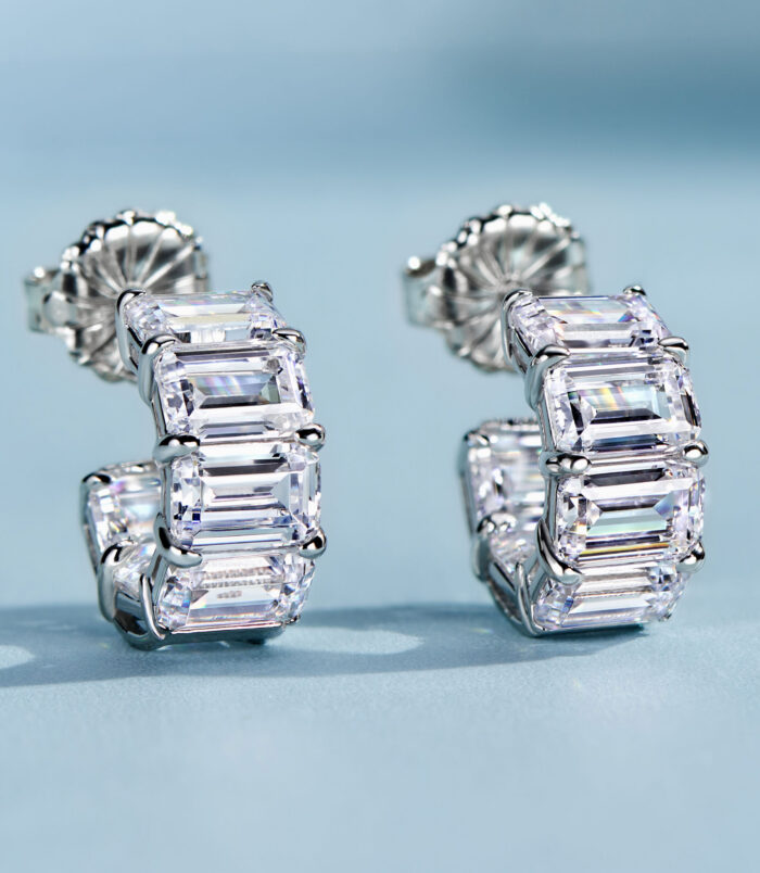 Chic sterling silver huggie hoop earrings, featuring a curved band encrusted with baguette-cut white cubic zirconia stones in a channel setting, creating a sleek and modern look perfect for adding a touch of glamour to any outfit.