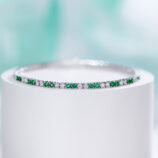 Sleek tennis-style sterling silver bracelet with alternating round green and clear stones, polished finish.