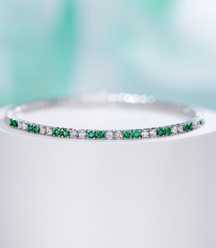 Sleek tennis-style sterling silver bracelet with alternating round green and clear stones, polished finish.