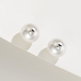 A pair of white pearl stud earrings with a small metallic star-shaped accent in the center, set in polished sterling silver.