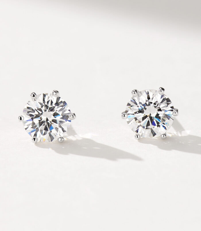 Classic six-prong Brilliant-Cut Sterling Silver Stud Earrings A pair of round, brilliant-cut stud earrings in polished sterling silver, featuring a central clear gemstone set in a classic six-prong setting, displayed against a soft white background.