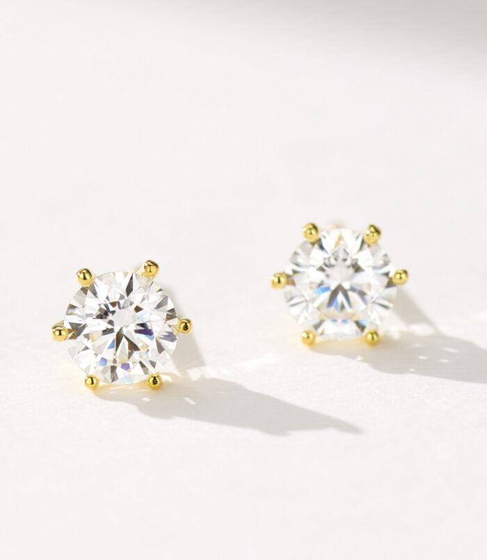 Classic Brilliant-Cut Sterling Silver Stud Earrings A pair of round, brilliant-cut stud earrings in polished sterling silver, featuring a central clear gemstone set in a classic six-prong setting, displayed against a soft white background.