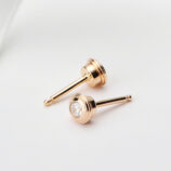 Sterling silver stud earrings with a round clear cubic zirconia center stone and a polished gold-toned setting