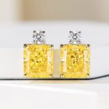 Sterling silver stud earrings with a large yellow cushion-cut center stone and a clear round halo.