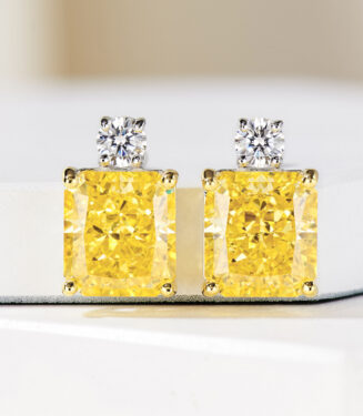 Sterling silver stud earrings with a large yellow cushion-cut center stone and a clear round halo.