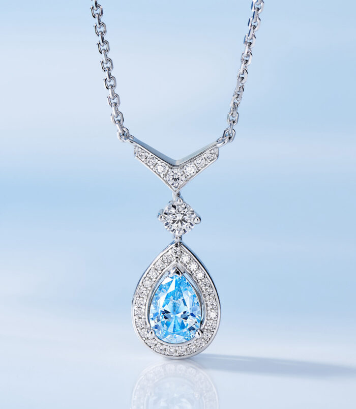 Exquisite sterling silver necklace, featuring a V-shaped top adorned with round brilliant-cut white cubic zirconia stones, suspending a pear-shaped blue cubic zirconia stone in a halo setting surrounded by round brilliant-cut white cubic zirconia stones, paired with a classic cable chain, creating a sophisticated and glamorous look perfect for adding a touch of luxury to any outfit.