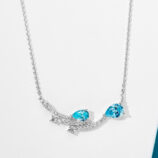 Enchanting sterling silver necklace, featuring a curved bar design adorned with two pear-shaped brilliant-cut blue cubic zirconia stones and a cluster of small round brilliant-cut white cubic zirconia stones, along with delicate star-shaped accents, paired with a classic cable chain, creating a whimsical and sophisticated look perfect for adding a touch of magic to any outfit.