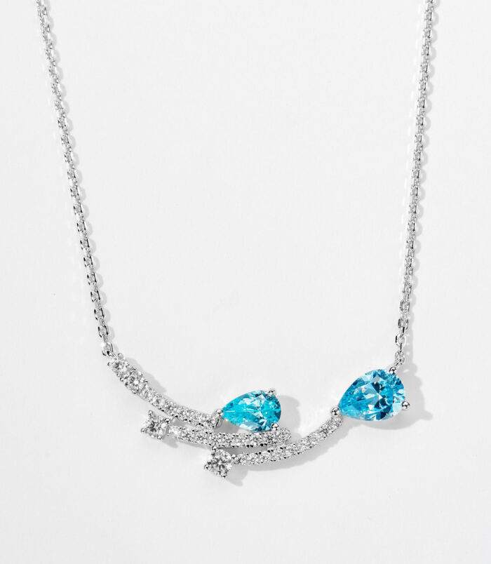 Sterling Silver Necklace with Blue Cubic Zirconia Stones and Star Accents Enchanting sterling silver necklace, featuring a curved bar design adorned with two pear-shaped brilliant-cut blue cubic zirconia stones and a cluster of small round brilliant-cut white cubic zirconia stones, along with delicate star-shaped accents, paired with a classic cable chain, creating a whimsical and sophisticated look perfect for adding a touch of magic to any outfit.