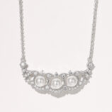 Elegant sterling silver necklace featuring a curved bar pendant adorned with three round white freshwater pearls, surrounded by a halo of round brilliant-cut white cubic zirconia stones, creating a sophisticated and timeless look perfect for adding a touch of classic elegance to any outfit.