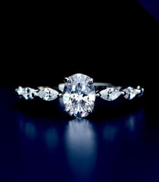 Exquisite sterling silver engagement ring featuring a large oval-cut cubic zirconia center stone in a four-prong setting, flanked by marquise-cut cubic zirconia accents along the polished band for a sophisticated and glamorous look.