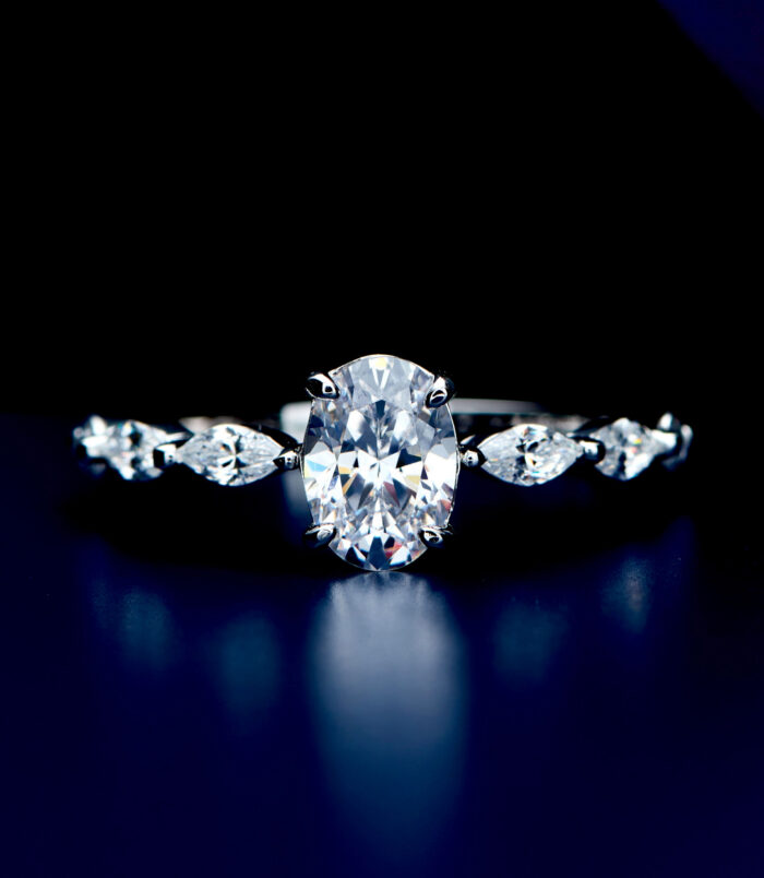 Exquisite sterling silver engagement ring featuring a large oval-cut cubic zirconia center stone in a four-prong setting, flanked by marquise-cut cubic zirconia accents along the polished band for a sophisticated and glamorous look.