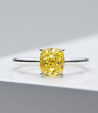 Elegant sterling silver ring featuring a large cushion-cut simulated yellow diamond center stone in a four-prong setting, paired with a sleek and simple band for a timeless and sophisticated look.