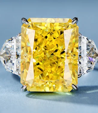 Three-stone sterling silver ring featuring a radiant yellow emerald-cut center stone, flanked by two trillion-cut white cubic zirconia accents, exuding luxury and sophistication.