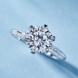 Classic solitaire sterling silver ring with a large round brilliant-cut cubic zirconia center stone, set in a six-prong setting, and accented with smaller pavé-set zircons along the band for timeless elegance.