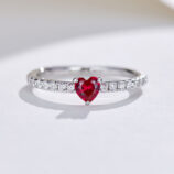 Romantic sterling silver ring with a heart-shaped simulated ruby center stone in a three-prong setting, paired with a pavé-set cubic zirconia band for a delicate and feminine look.