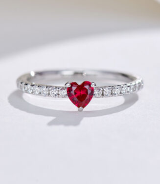 Romantic sterling silver ring with a heart-shaped simulated ruby center stone in a three-prong setting, paired with a pavé-set cubic zirconia band for a delicate and feminine look.