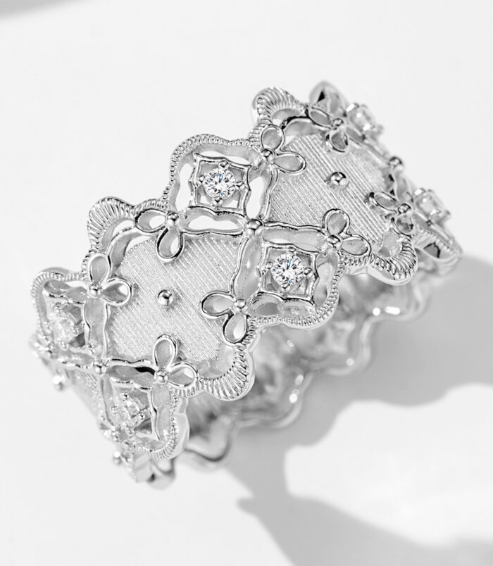 Intricate vintage-inspired sterling silver band ring featuring an openwork floral design with delicate milgrain detailing, round brilliant-cut cubic zirconia accents, and a textured brushed silver center, creating a romantic and sophisticated look perfect for adding a touch of vintage charm to any outfit.