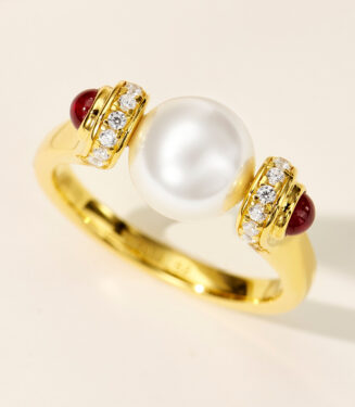 Elegant gold-plated sterling silver ring featuring a large, lustrous white pearl at the center, flanked by two deep red cabochon stones and sparkling round brilliant-cut cubic zirconia accents, creating a sophisticated and timeless look perfect for formal occasions or adding a touch of luxury to everyday wear.