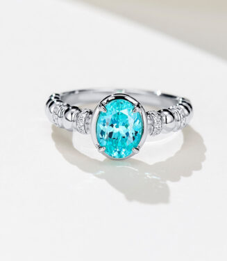 Vintage-inspired sterling silver ring with a vibrant oval-cut paraiba tourmaline center stone, set in a bezel setting, and accented with milgrain details and pavé-set cubic zirconia along the twisted rope band for a unique and elegant look.