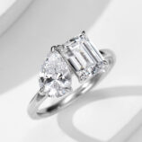 Elegant two-stone sterling silver ring featuring a large pear-shaped brilliant-cut white cubic zirconia stone and an emerald-cut white cubic zirconia stone set in a sleek and modern band, creating a sophisticated and eye-catching look perfect for engagements, anniversaries, or special occasions.