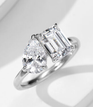 Elegant two-stone sterling silver ring featuring a large pear-shaped brilliant-cut white cubic zirconia stone and an emerald-cut white cubic zirconia stone set in a sleek and modern band, creating a sophisticated and eye-catching look perfect for engagements, anniversaries, or special occasions.