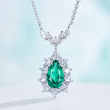 Exquisite sterling silver necklace featuring a large pear-cut green cubic zirconia stone at the center, surrounded by a halo of round brilliant-cut white cubic zirconia stones, topped with a decorative bail adorned with marquise-cut white cubic zirconia stones, creating a dazzling and sophisticated look perfect for adding a touch of elegance to any outfit.