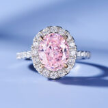 Elegant halo-style sterling silver ring with a large oval-cut pink gemstone center, surrounded by a double halo of sparkling cubic zirconia stones for a glamorous and luxurious look.