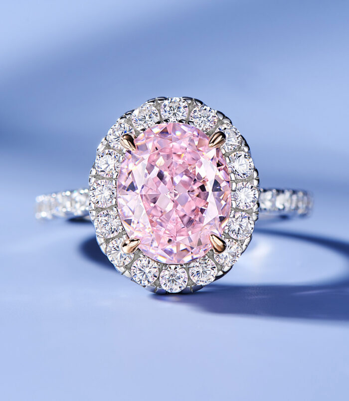 Elegant halo-style sterling silver ring with a large oval-cut pink gemstone center, surrounded by a double halo of sparkling cubic zirconia stones for a glamorous and luxurious look.