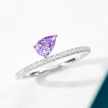 Elegant sterling silver engagement ring featuring a single pear-cut amethyst cubic zirconia center stone set in a four-prong setting, paired with a pavé-set band of round brilliant-cut white cubic zirconia stones, creating a romantic and feminine look perfect for engagements, anniversaries, or adding a touch of color to everyday wear.