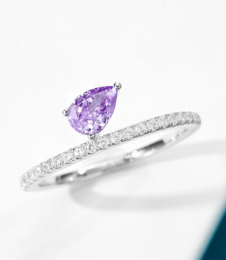 Elegant sterling silver engagement ring featuring a single pear-cut amethyst cubic zirconia center stone set in a four-prong setting, paired with a pavé-set band of round brilliant-cut white cubic zirconia stones, creating a romantic and feminine look perfect for engagements, anniversaries, or adding a touch of color to everyday wear.