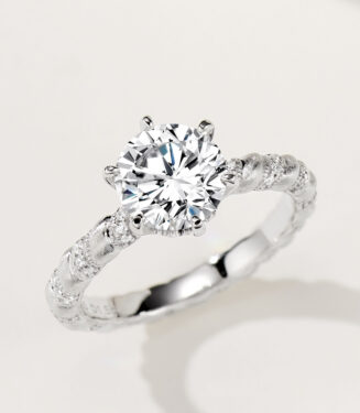 Rustic-inspired sterling silver engagement ring with a large round brilliant-cut cubic zirconia center stone in a four-prong setting, featuring a bark-textured band with pavé-set cubic zirconia accents for a nature-inspired and unique look.