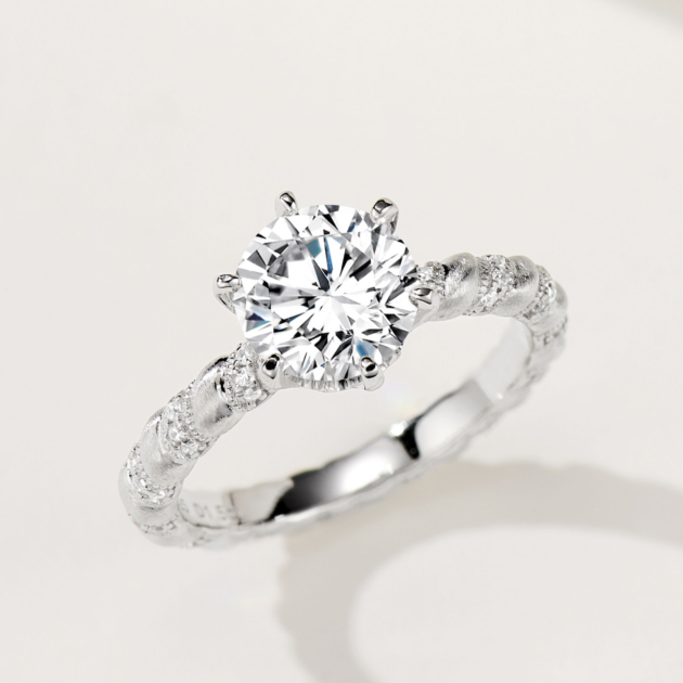 Rustic-inspired sterling silver engagement ring with a large round brilliant-cut cubic zirconia center stone in a four-prong setting, featuring a bark-textured band with pavé-set cubic zirconia accents for a nature-inspired and unique look.