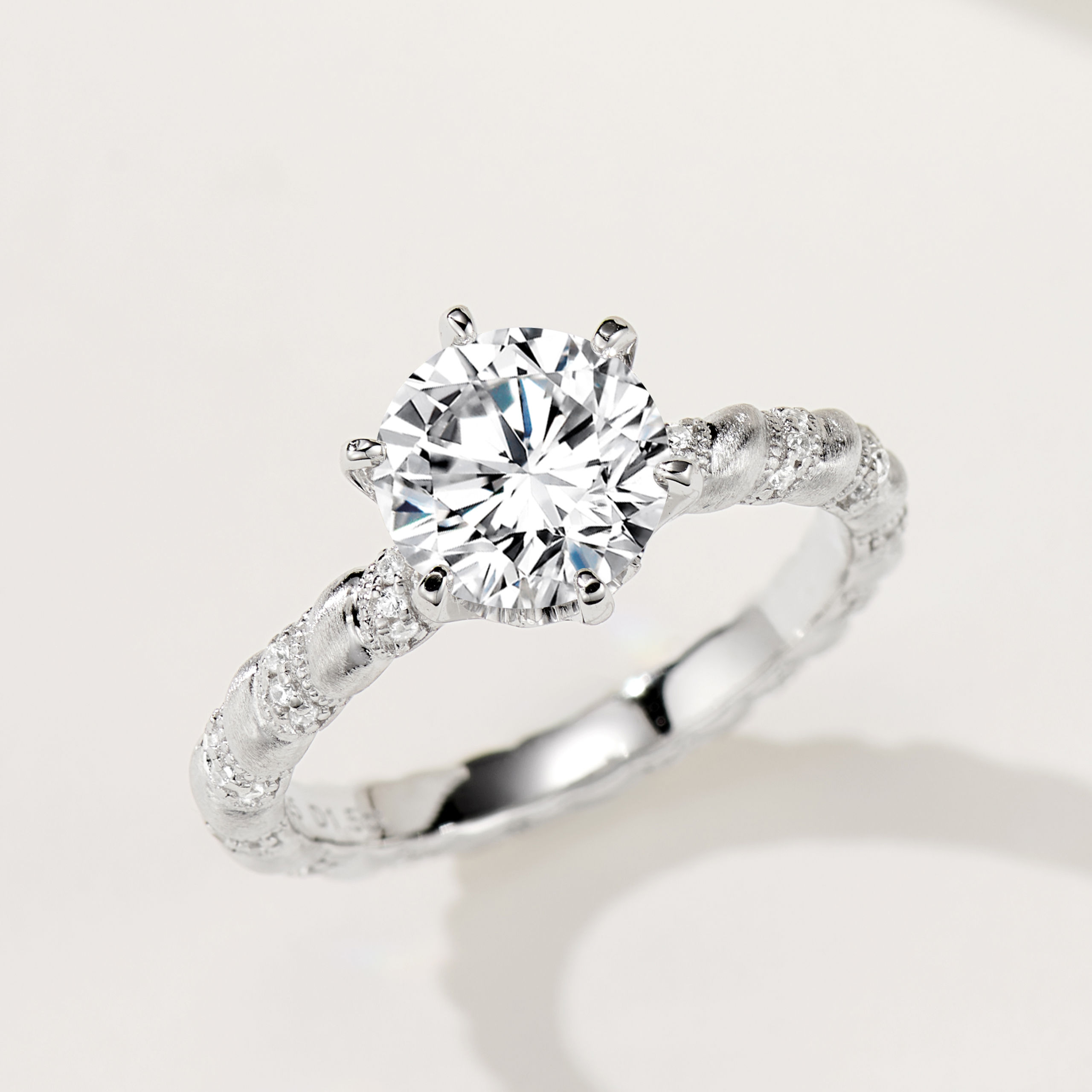 Rustic-inspired sterling silver engagement ring with a large round brilliant-cut cubic zirconia center stone in a four-prong setting, featuring a bark-textured band with pavé-set cubic zirconia accents for a nature-inspired and unique look.