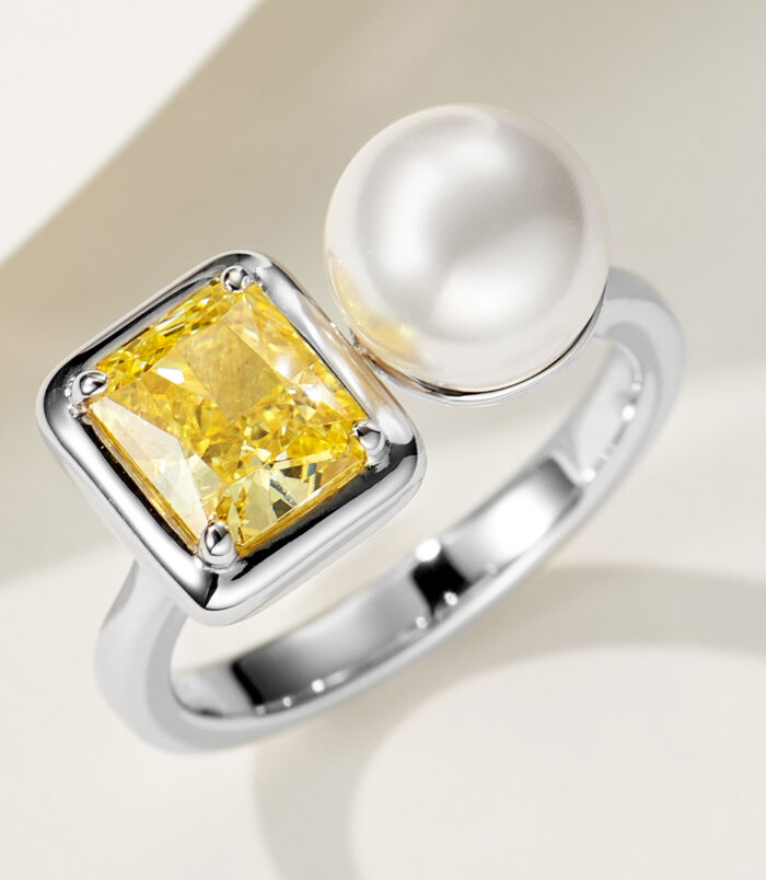 Bold Two-Stone Open Sterling Silver Ring with Emerald-Cut Yellow Cubic Zirconia and White Pearl Modern two-stone open sterling silver ring featuring a large emerald-cut yellow cubic zirconia stone set in a bezel setting and a lustrous white pearl, creating a bold and contemporary look perfect for adding a touch of luxury to any outfit.