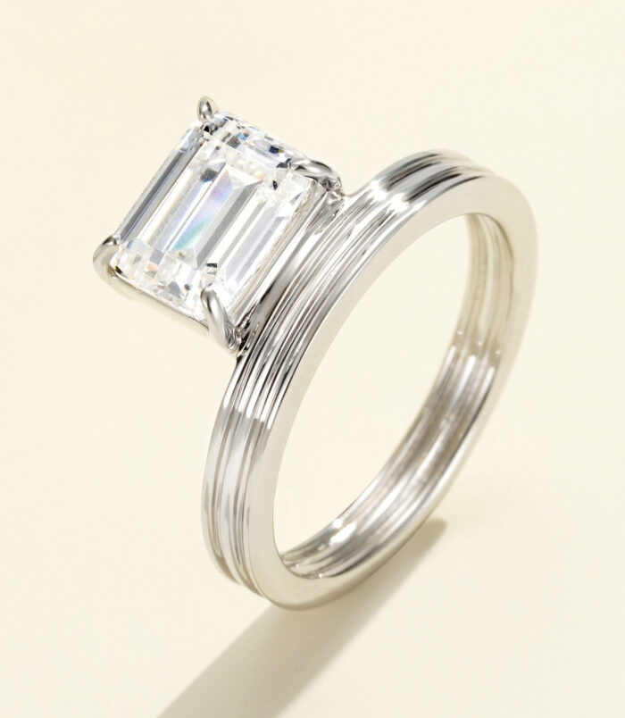 Bold and modern sterling silver ring featuring a large emerald-cut cubic zirconia center stone in a four-prong setting, paired with a wide, textured band with vertical grooves for a sophisticated and contemporary look.