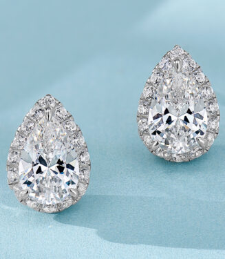Elegant sterling silver stud earrings, featuring a large pear-shaped brilliant-cut white cubic zirconia stone as the centerpiece, surrounded by a halo of small round brilliant-cut white cubic zirconia stones, creating a timeless and sophisticated look perfect for adding a touch of glamour to any outfit.