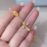 handheld close-up of orange cross silver bracelet, highlighting the details of cross cluster.